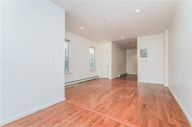 empty room featuring light wood-style flooring, electric panel, recessed lighting, and baseboard heating