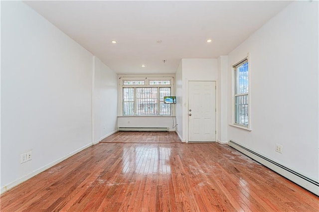 unfurnished room featuring a baseboard heating unit, recessed lighting, baseboard heating, and hardwood / wood-style floors