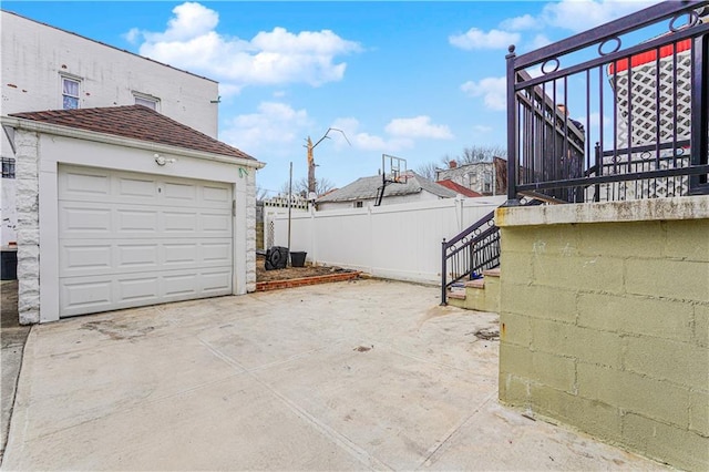 view of patio with concrete driveway, stairs, and fence