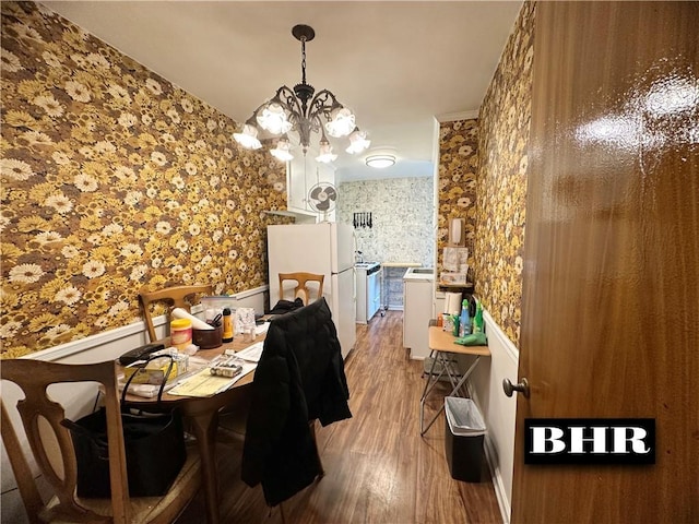 dining area featuring wainscoting, wood finished floors, an inviting chandelier, and wallpapered walls