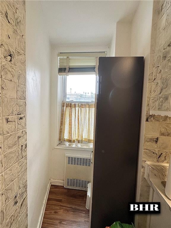 kitchen featuring freestanding refrigerator, radiator, baseboards, and wood finished floors