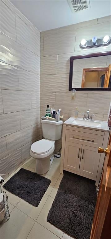 half bathroom with toilet, tile walls, visible vents, and tile patterned floors