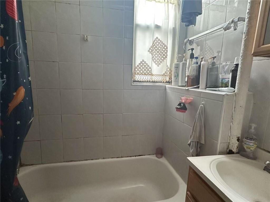 bathroom with shower / bathtub combination with curtain, vanity, and a healthy amount of sunlight