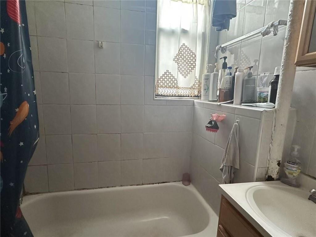 bathroom with a wealth of natural light, vanity, and shower / bath combo with shower curtain