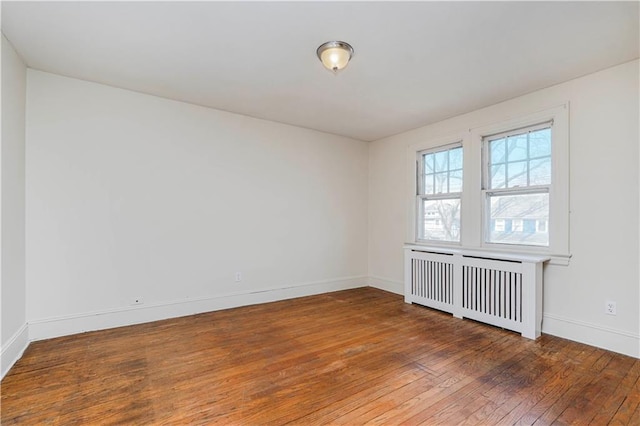 unfurnished room with radiator, baseboards, and hardwood / wood-style floors