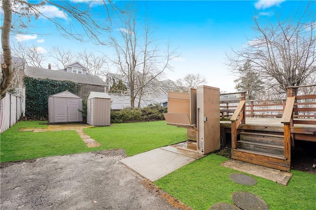 view of yard featuring a storage shed, an outdoor structure, fence private yard, and a wooden deck