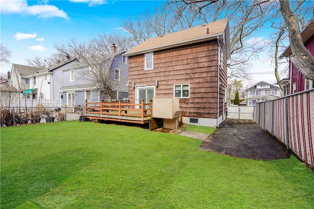 back of house with a fenced backyard, a residential view, a chimney, a deck, and a yard