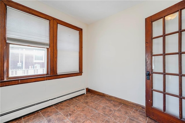 unfurnished room featuring a baseboard heating unit and baseboards