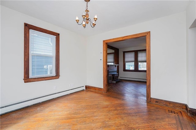 unfurnished room with baseboard heating, an inviting chandelier, a baseboard heating unit, wood finished floors, and baseboards