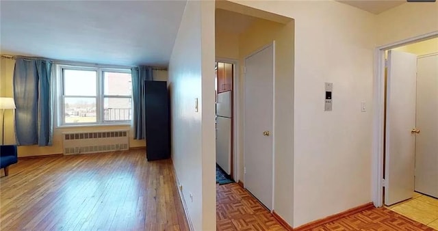 hallway featuring radiator heating unit and parquet flooring