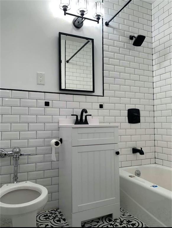 bathroom with tile walls, tile patterned floors, vanity, and  shower combination