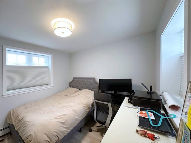 bedroom with a baseboard radiator and wood finished floors