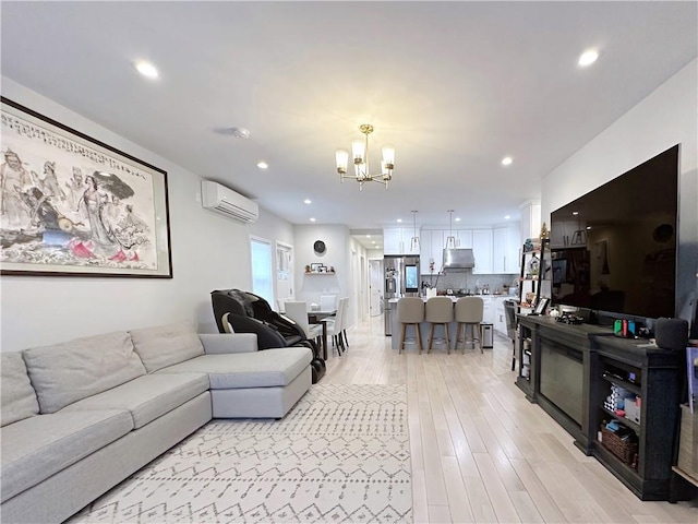 living area with a notable chandelier, a wall mounted AC, light wood-type flooring, and recessed lighting