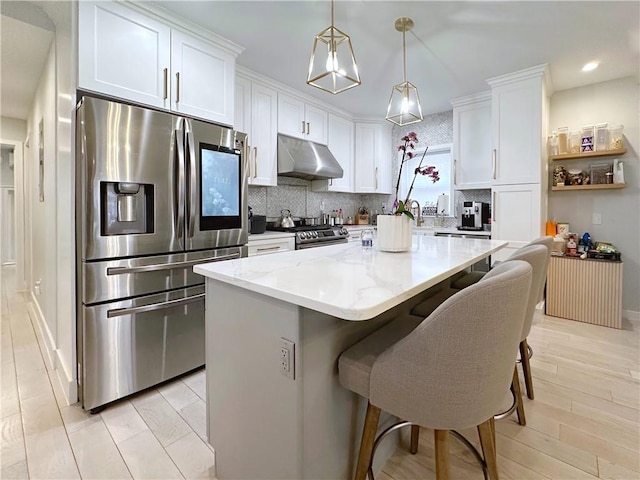 kitchen with a center island, stainless steel appliances, backsplash, white cabinets, and under cabinet range hood