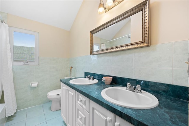 bathroom with toilet, tile walls, vaulted ceiling, and a sink