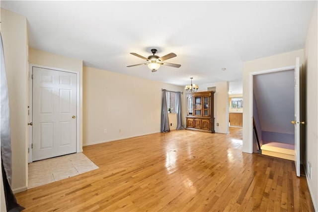 unfurnished living room with light wood-style flooring, baseboards, and ceiling fan with notable chandelier