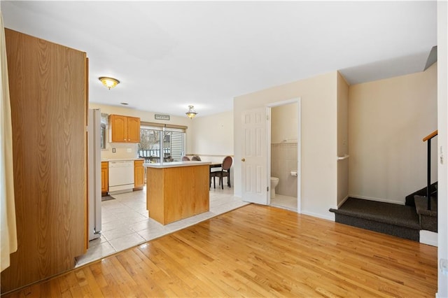 kitchen with a kitchen island, light wood-type flooring, light countertops, and dishwasher