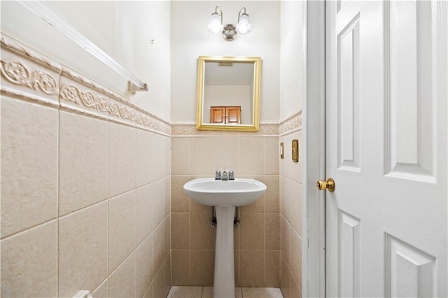 half bath with a wainscoted wall and tile walls