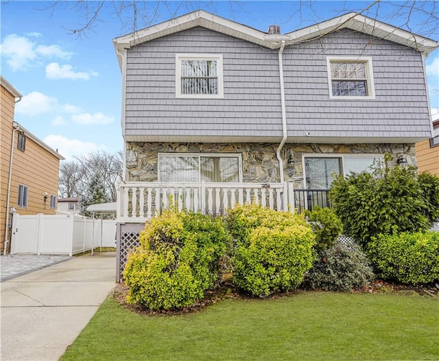 view of front of property featuring stone siding, fence, and a front yard