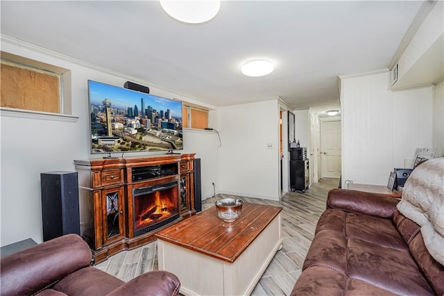 living area with light wood-style floors, a warm lit fireplace, and visible vents