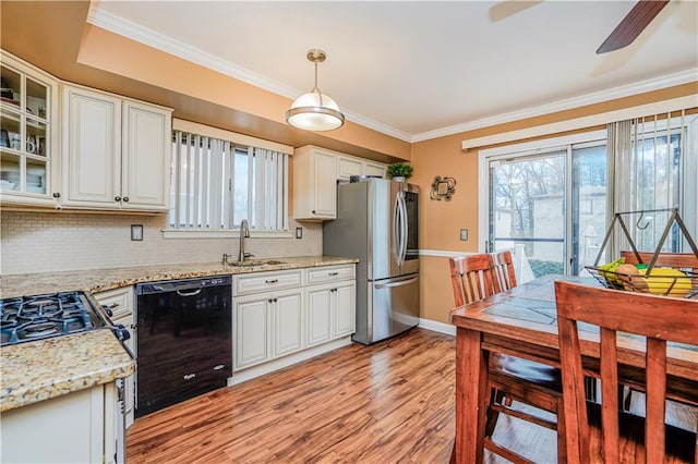 kitchen featuring black dishwasher, ornamental molding, a sink, and freestanding refrigerator