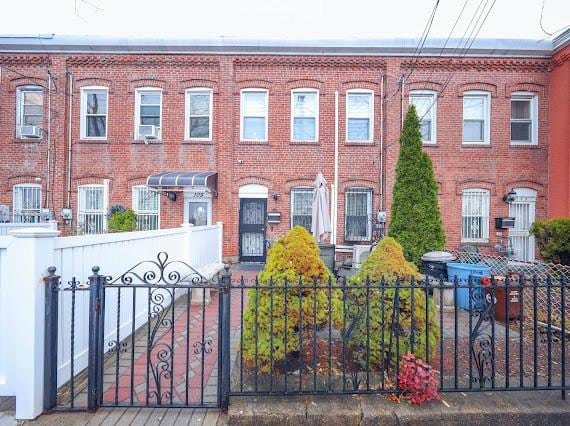 townhome / multi-family property featuring a fenced front yard and brick siding