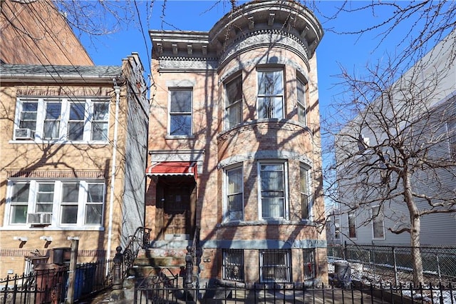 italianate-style house with a fenced front yard and brick siding