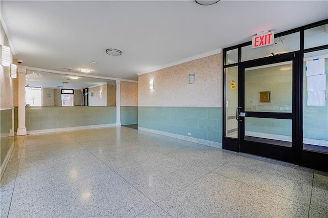 spare room with concrete block wall, wallpapered walls, crown molding, and speckled floor