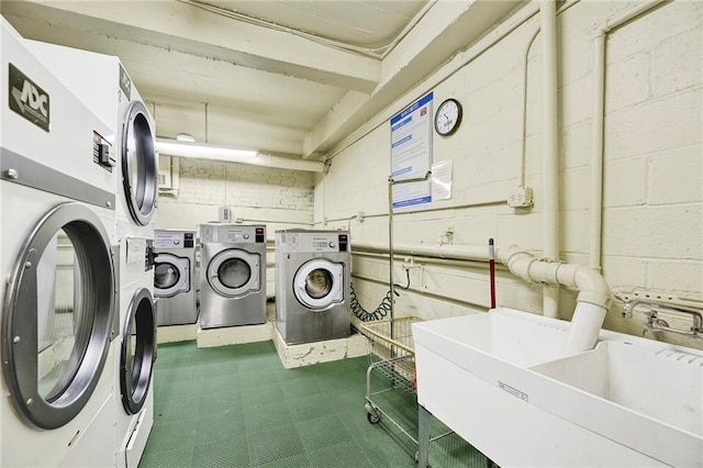 shared laundry area with washer and dryer, tile patterned floors, concrete block wall, and a sink