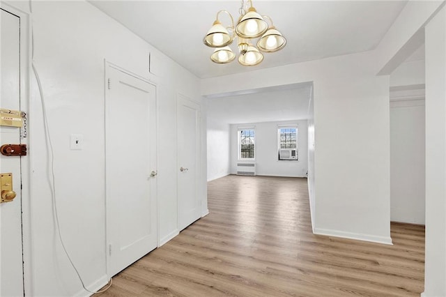 interior space with baseboards, light wood finished floors, and an inviting chandelier