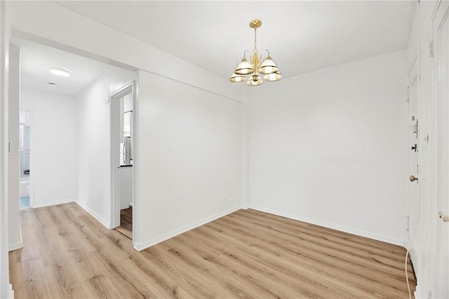 empty room featuring an inviting chandelier, baseboards, and light wood-type flooring