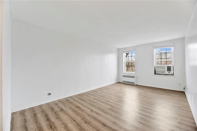 unfurnished room with cooling unit, radiator heating unit, baseboards, and wood finished floors