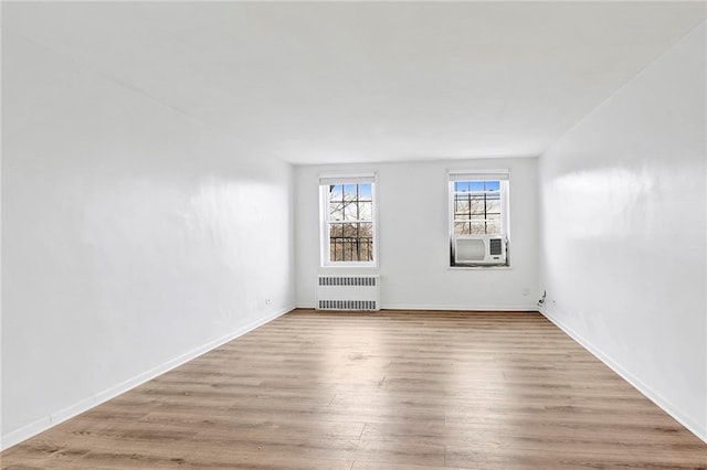 spare room with cooling unit, radiator, baseboards, and wood finished floors