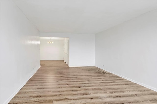 spare room featuring wood finished floors and a notable chandelier