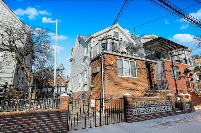 view of front of property featuring brick siding, a fenced front yard, and a balcony