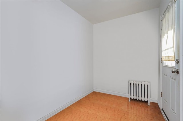 spare room with baseboards, light wood finished floors, and radiator heating unit