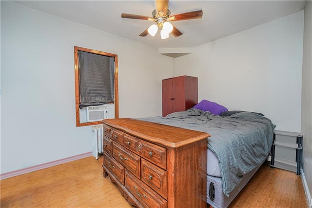 bedroom featuring light wood finished floors, radiator heating unit, baseboards, and a ceiling fan