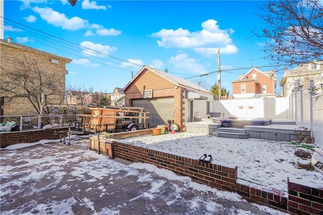 snowy yard with a garage, an outdoor structure, and fence