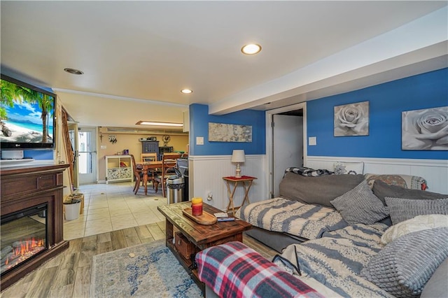 living area with a wainscoted wall, recessed lighting, wood finished floors, and a glass covered fireplace