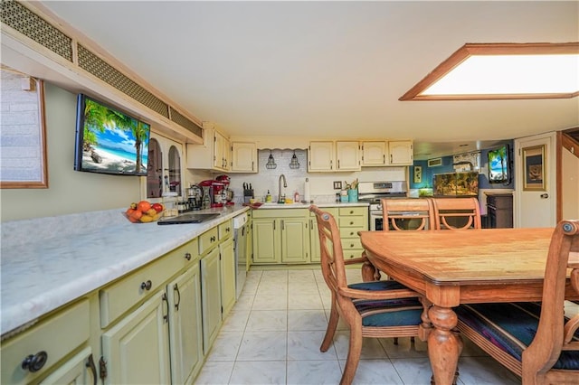 kitchen featuring appliances with stainless steel finishes, light countertops, a sink, and green cabinets