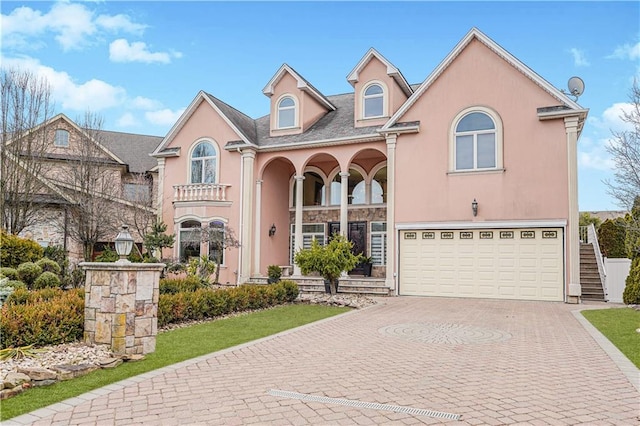 view of front facade with decorative driveway, an attached garage, and stucco siding