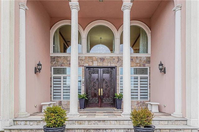 doorway to property with french doors, stone siding, and stucco siding