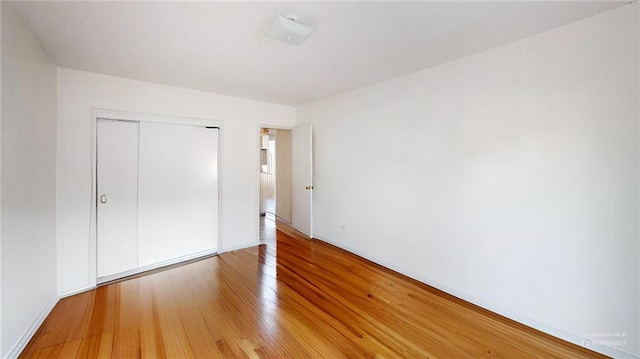 unfurnished bedroom with light wood-style flooring, a closet, and baseboards