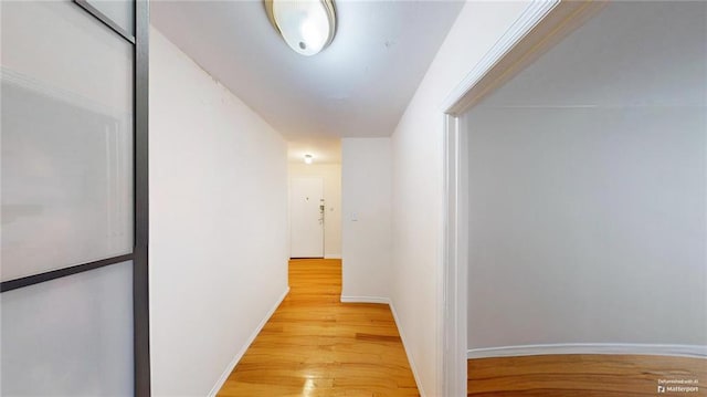 hallway with light wood-style floors and baseboards