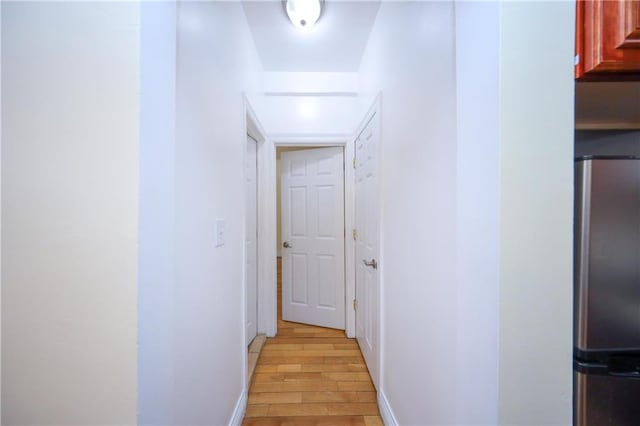 corridor with baseboards and light wood-style flooring