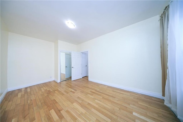 unfurnished bedroom featuring a closet, baseboards, and light wood-style floors