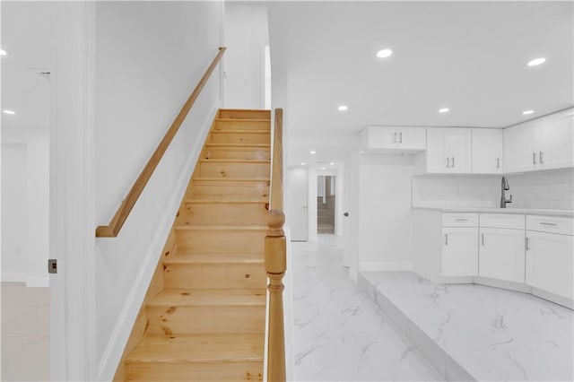 stairway with recessed lighting, marble finish floor, and baseboards