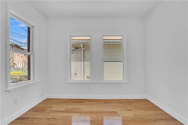 spare room with baseboards and light wood-style floors