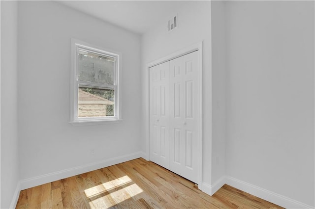 unfurnished bedroom featuring light wood-style floors, visible vents, a closet, and baseboards