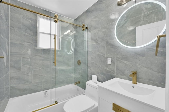 full bathroom featuring vanity, tile walls, toilet, and bath / shower combo with glass door